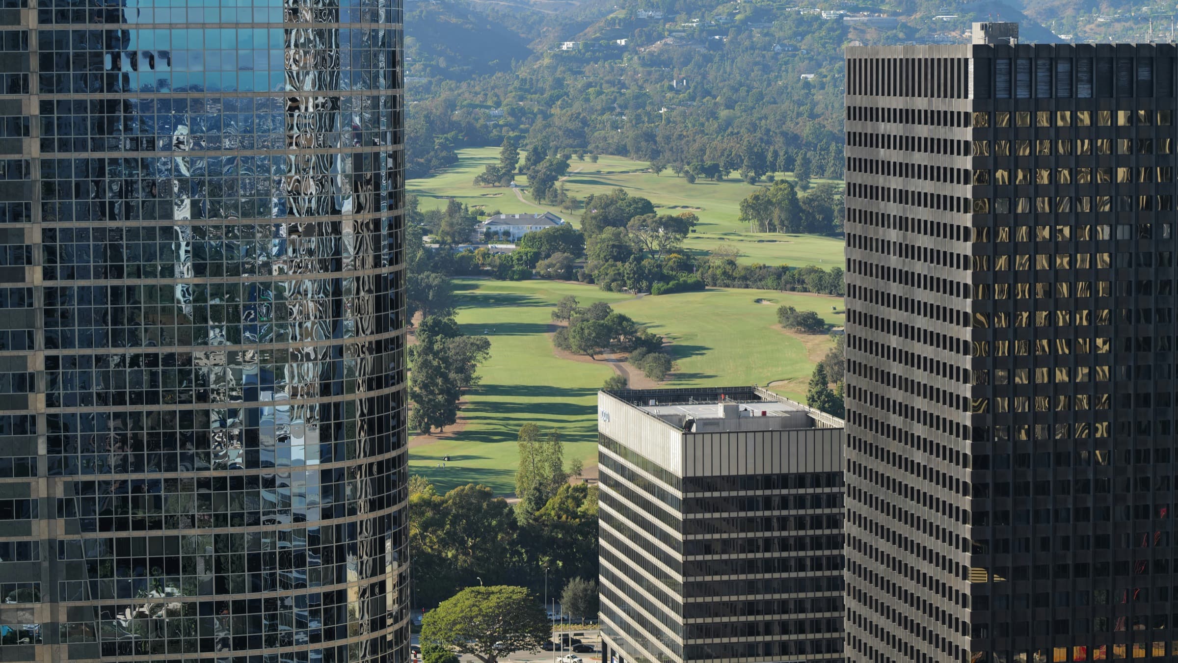 A golf course peaking through a city skyline.